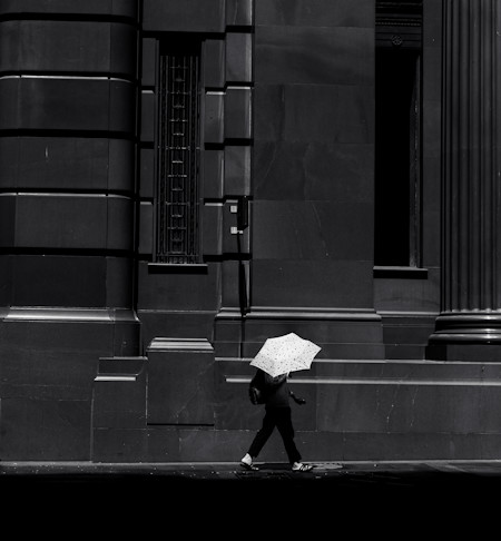 A figure with white umbrella walking